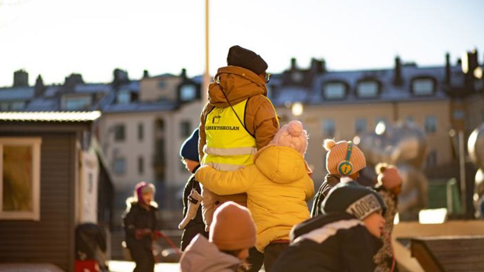 En vuxen och barn i rörelse på skolgård