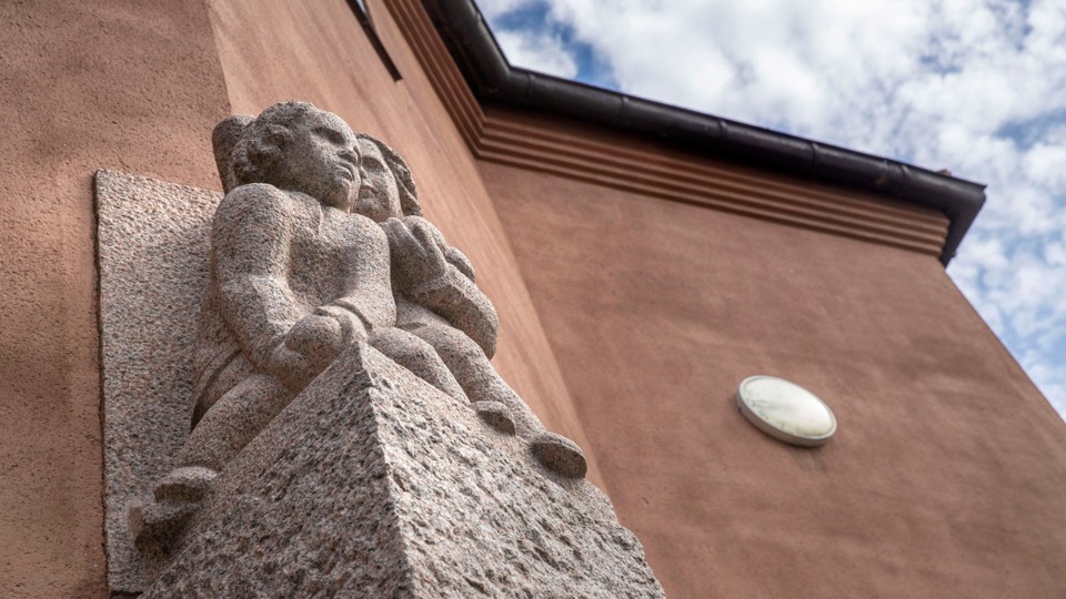 Staty av två barn i sten på tegelfärgad byggnad