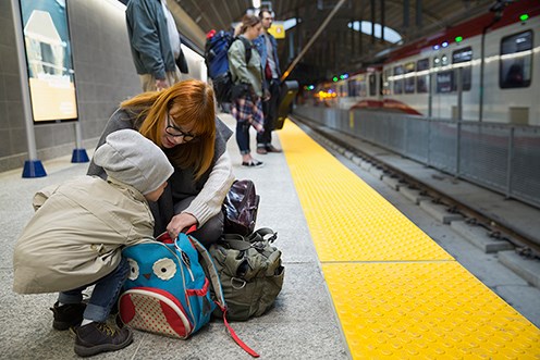 En kvinna och ett barn rotar bland väskor och ryggsätt på en tågperrong.