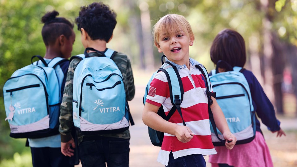 Fyra barn på promenad med ljusblå ryggsäckar med texten Vittra på.